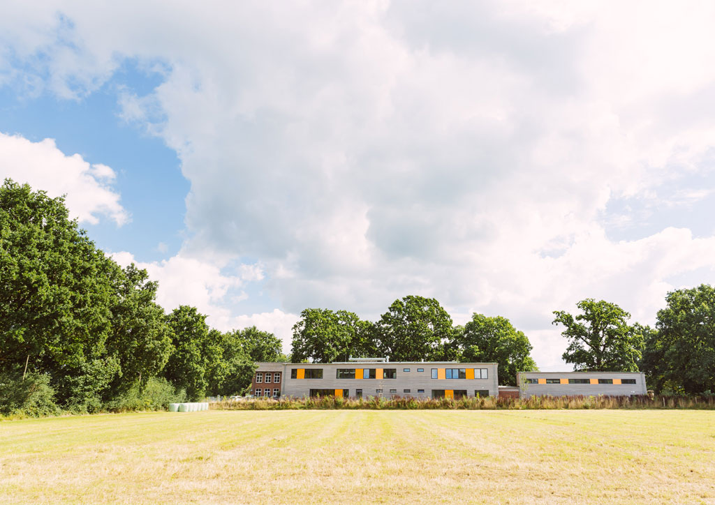 Das Bild zeigt das neue Schulgebäude der Schule Lehmkuhle. Davor befindet sich eine große Wiese.